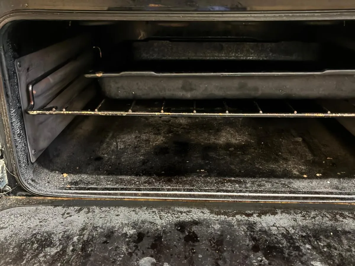 An oven interior coated in baked-on grease before cleaning