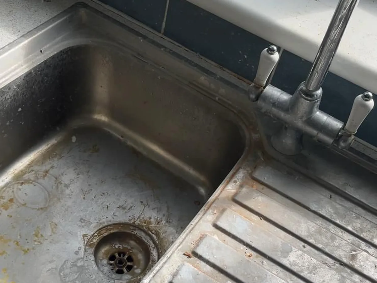 A stainless steel sink and tap dulled with limescale and grime before cleaning